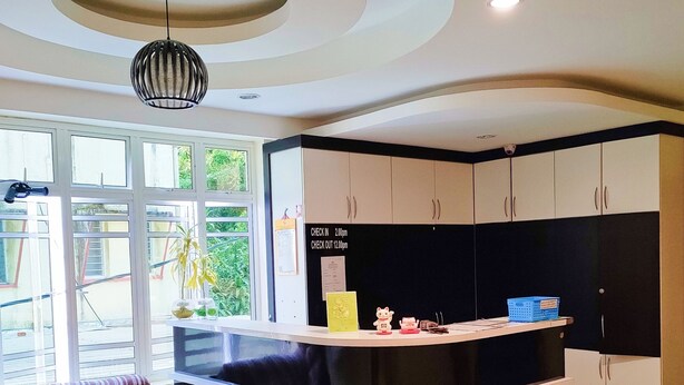 Una cocina moderna con una paleta de colores blanco y negro, un mostrador de recepción y un área de estar con sofá y reposapiés.