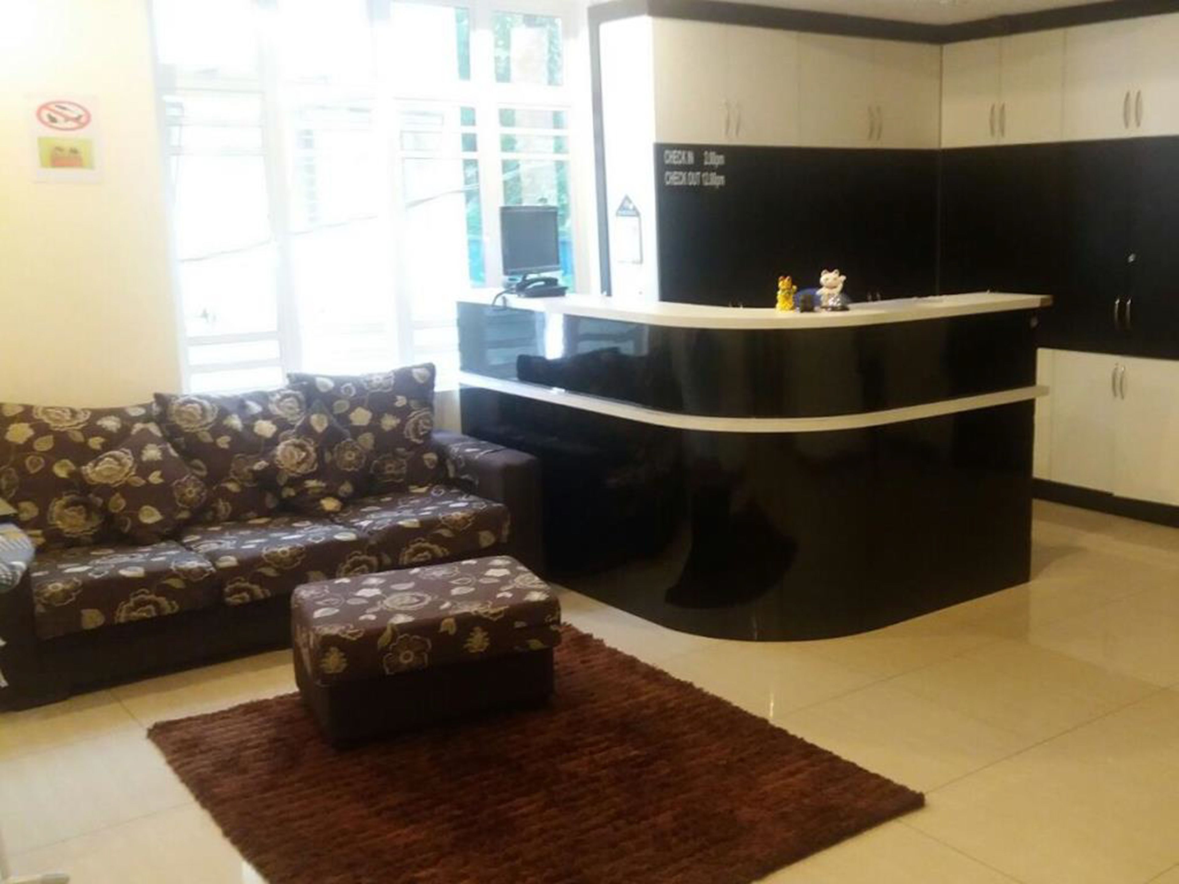 A living room with a sofa, ottoman, and a kitchen area with cabinets and a counter.