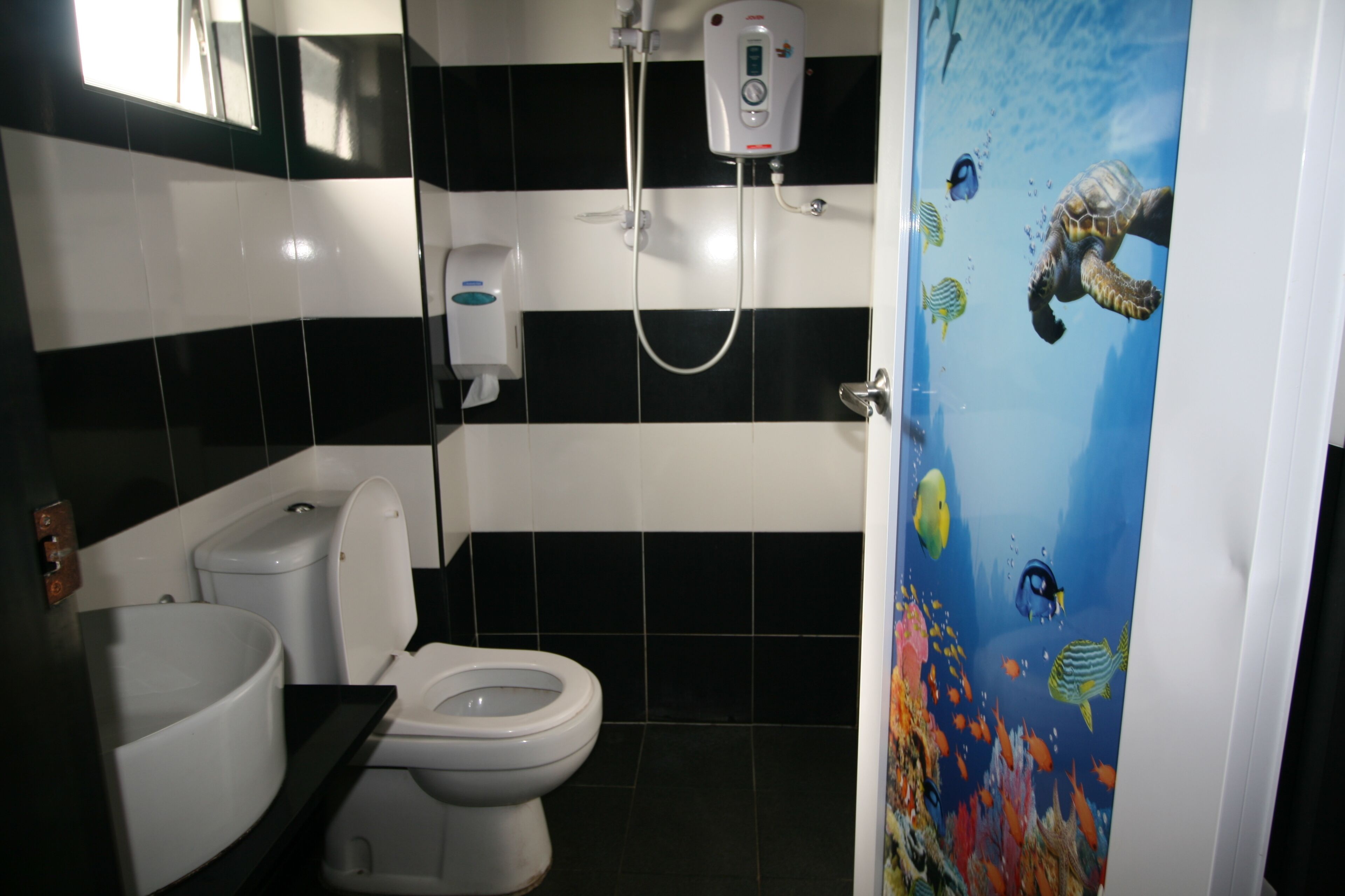 Une salle de bain équipée de toilettes, d’un lavabo et d’une douche avec un panneau de commande.