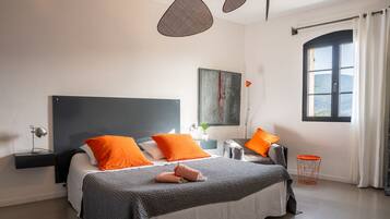 A modern bedroom with a large bed, two side tables, a window with curtains, and a painting on the wall.