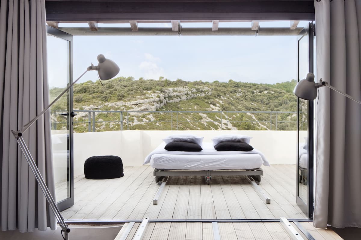 Varanda com cama, duas luminárias e vista para uma paisagem montanhosa.