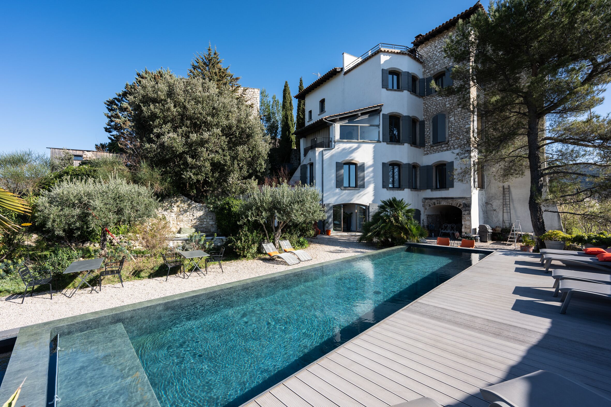 A modern building with a swimming pool, outdoor seating, and a well-maintained garden.