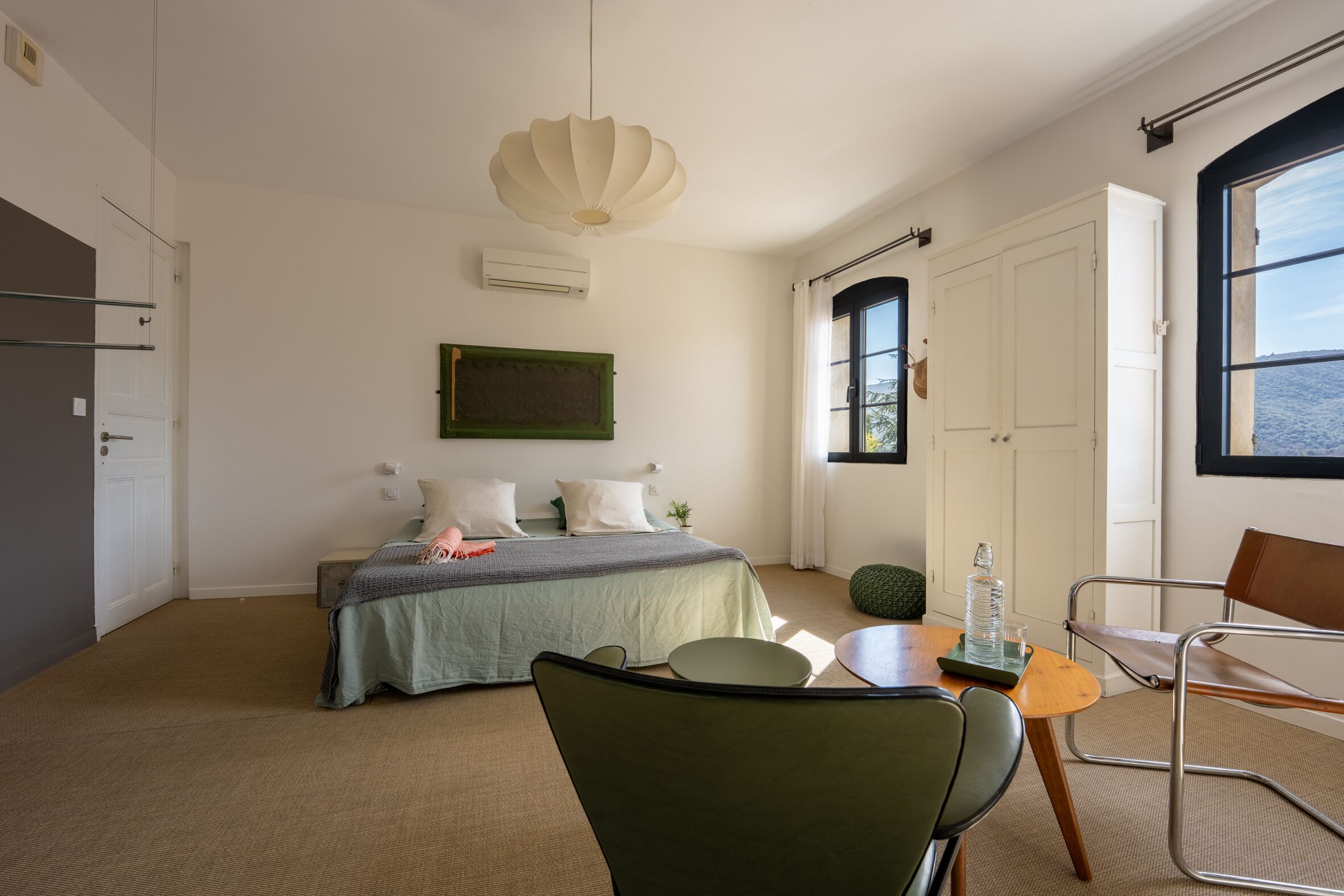 Een slaapkamer met een bed, een stoel, een tafel en een raam.