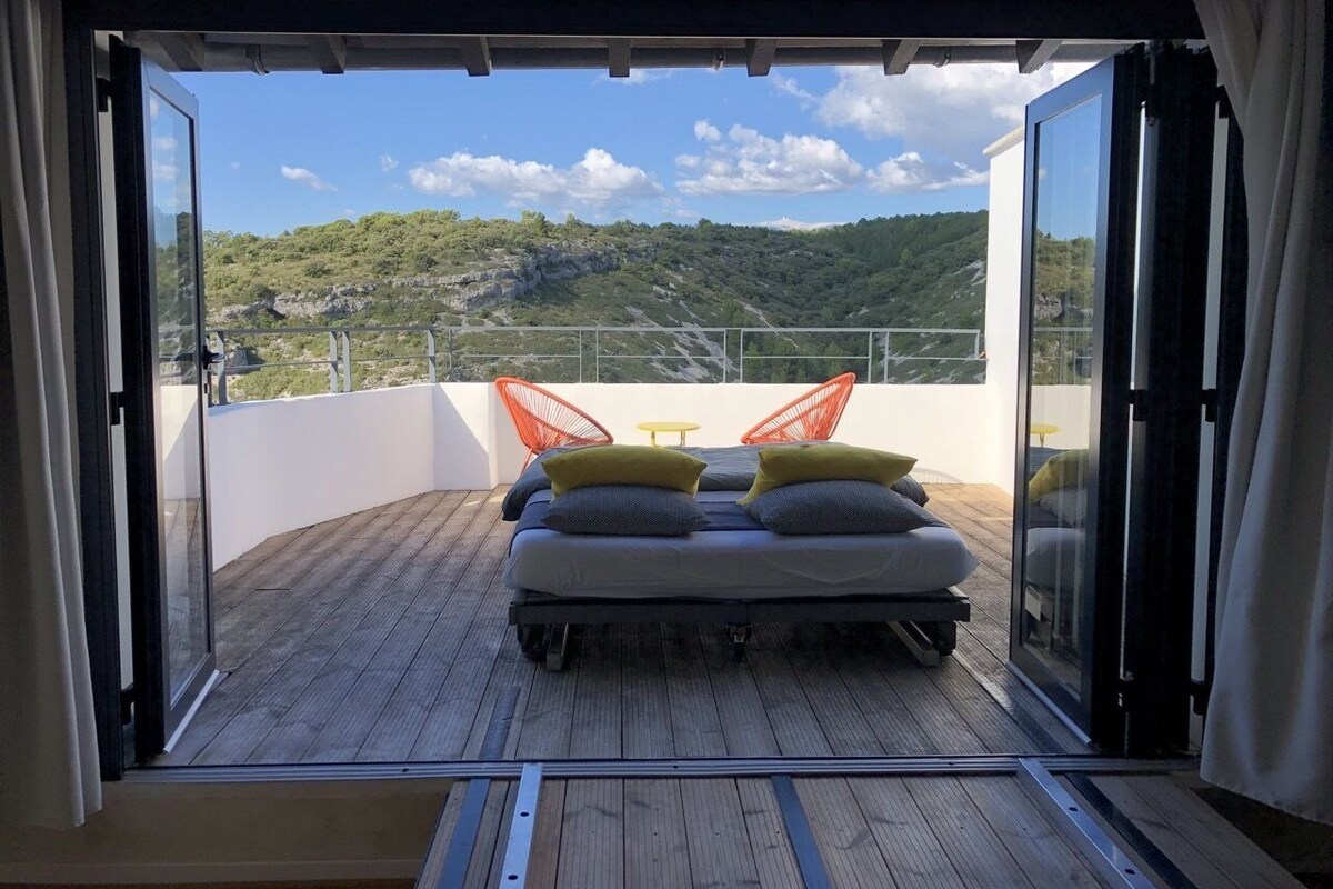 A balcony with a bed, a table, and chairs.