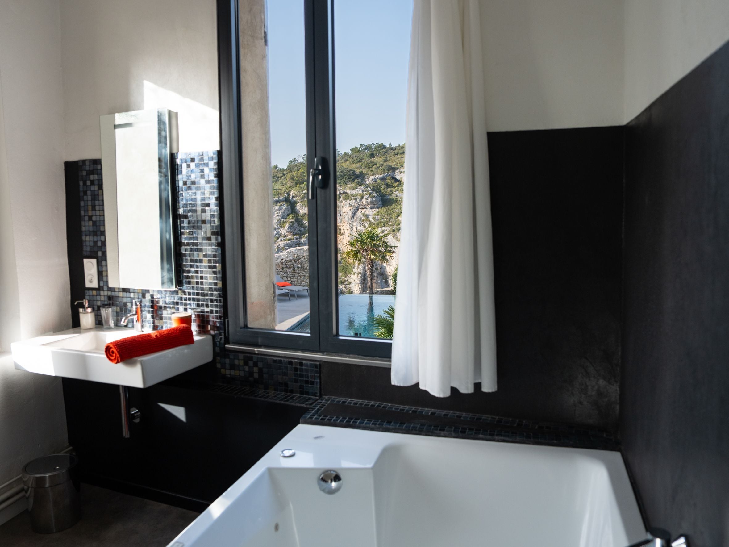 Un bany modern amb una banyera, un lavabo i una finestra gran.