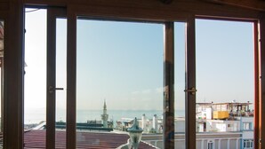 A table with various fruits and a view of a coastal city through large windows. - Mevlana Hotel (Istanbul)