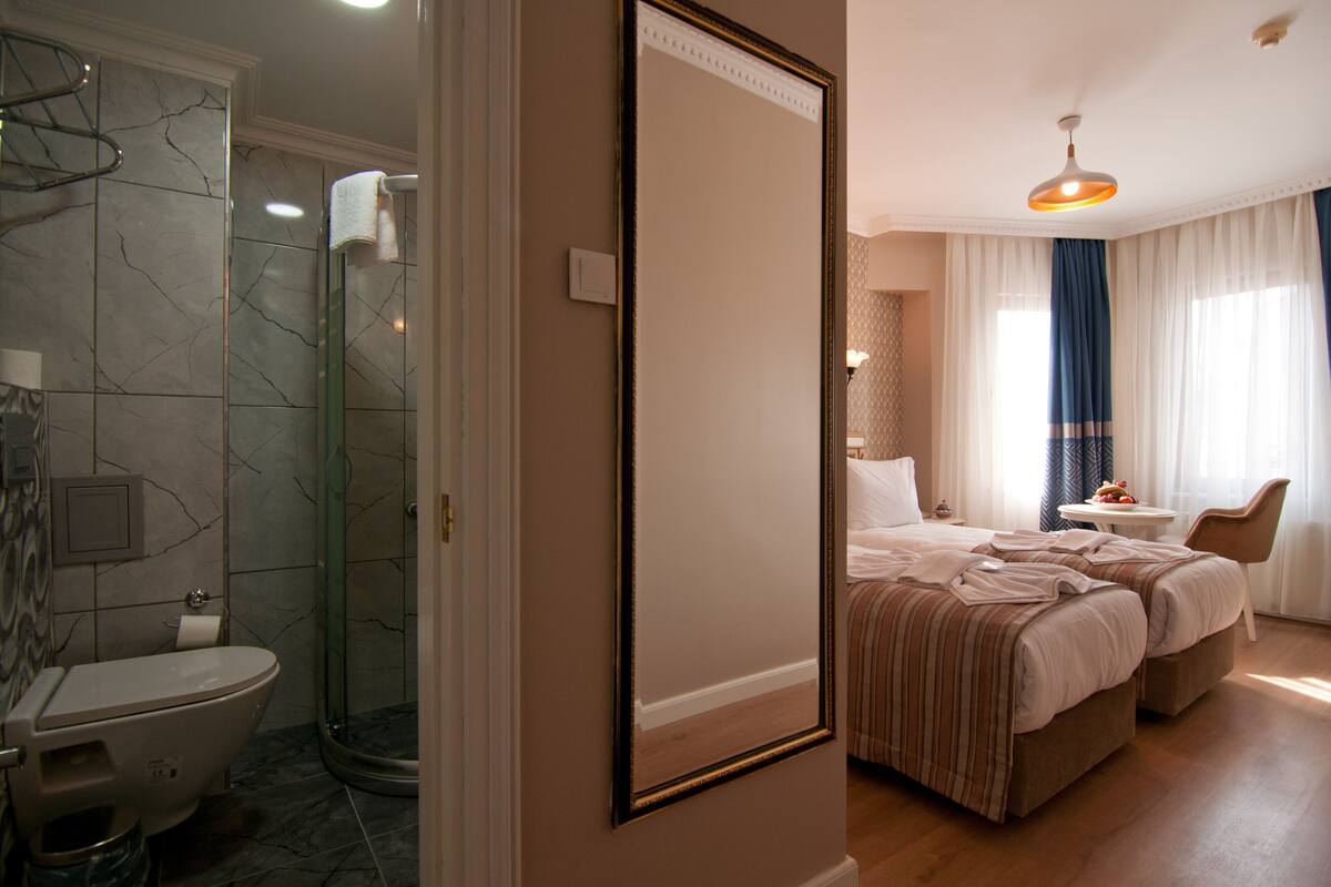 A hotel room with a bathroom, a bed, a chair, and a small table.