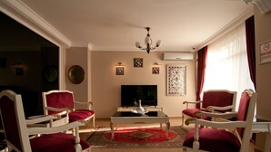 A living room with a television, two armchairs, a coffee table, and a chandelier. - Mevlana Hotel (Istanbul)