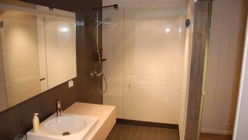 A modern bathroom with a large mirror, a sink, and a shower area.
