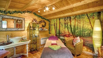 Relax in a serene space with a massage table, seating area, and forest views.