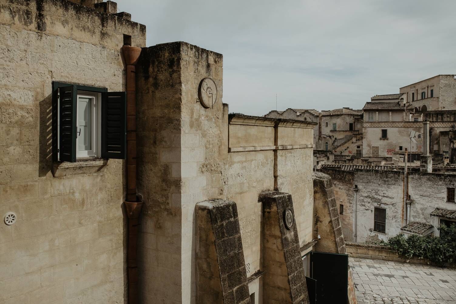 A narrow alleyway with old buildings, a visible door, and a clock on one of the buildings.