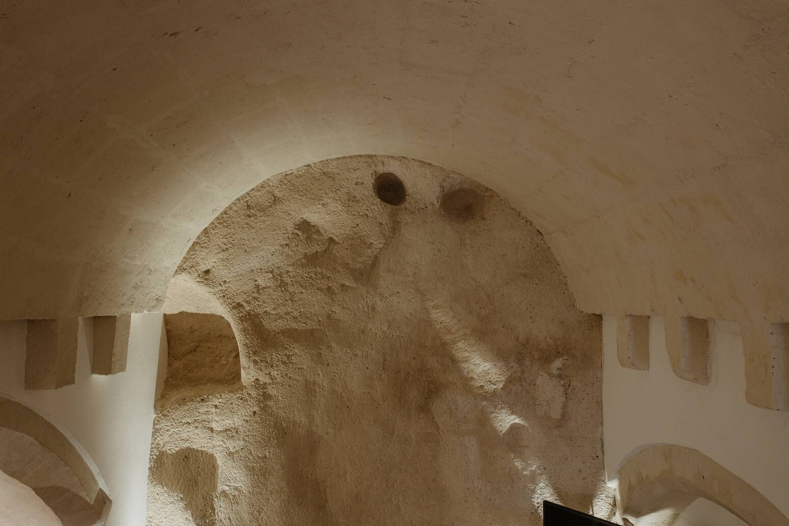 An arched doorway with rough, textured walls and a small circular window.