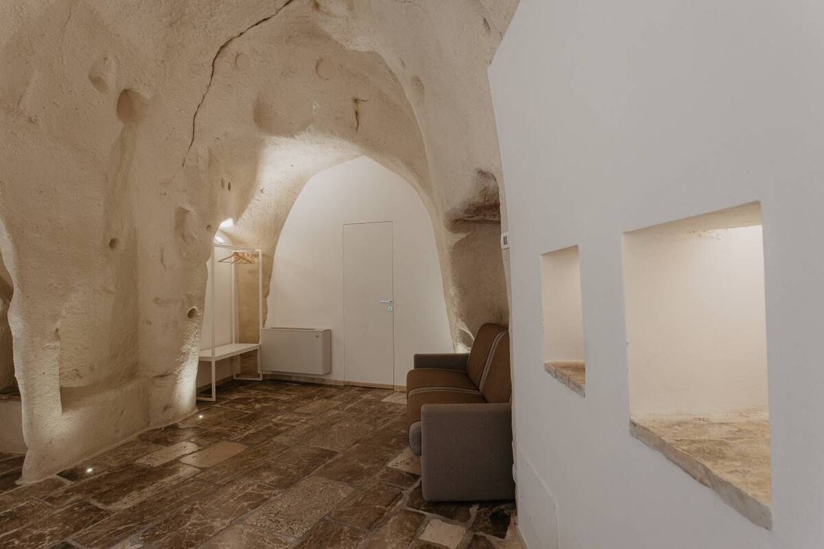 An interior with a stone archway, a door, a seating area, and a wall-mounted shelf.