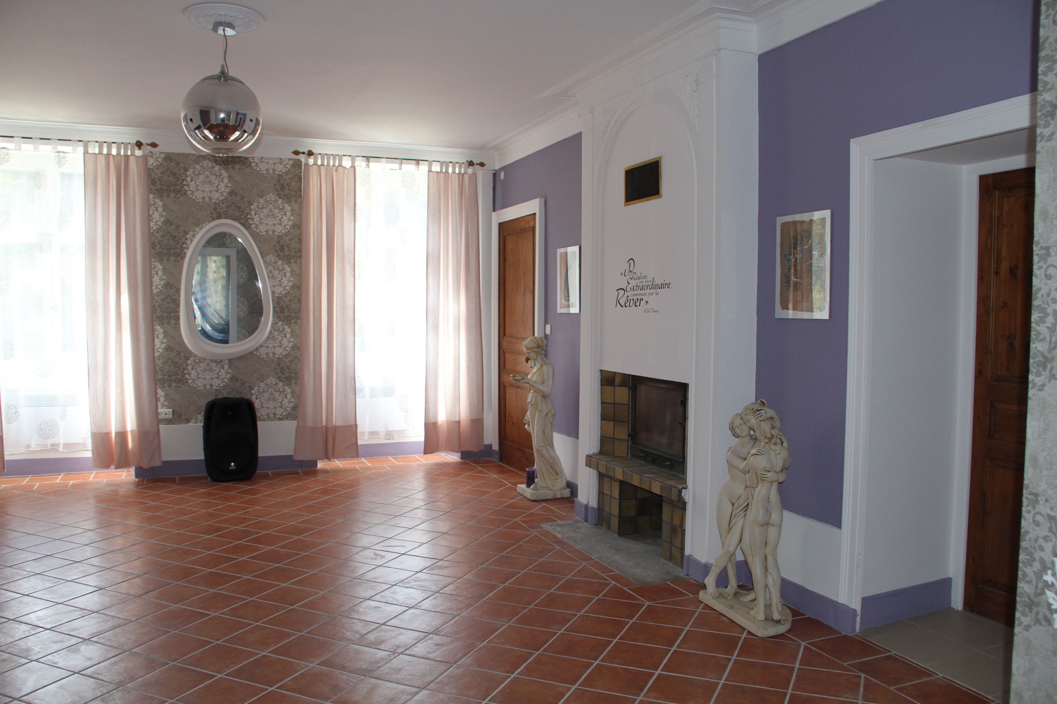 Una habitación amplia con piso de baldosas, chimenea y una estatua.