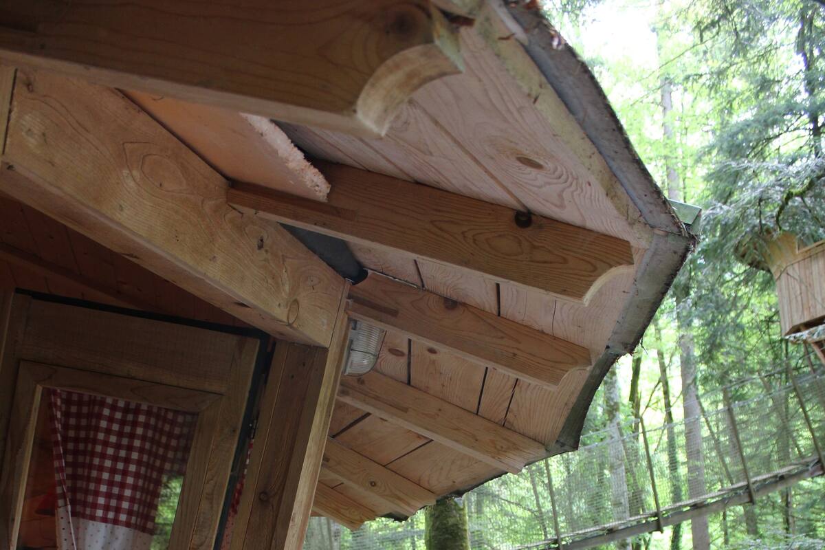 A wooden deck with a chair and a view of a forest.