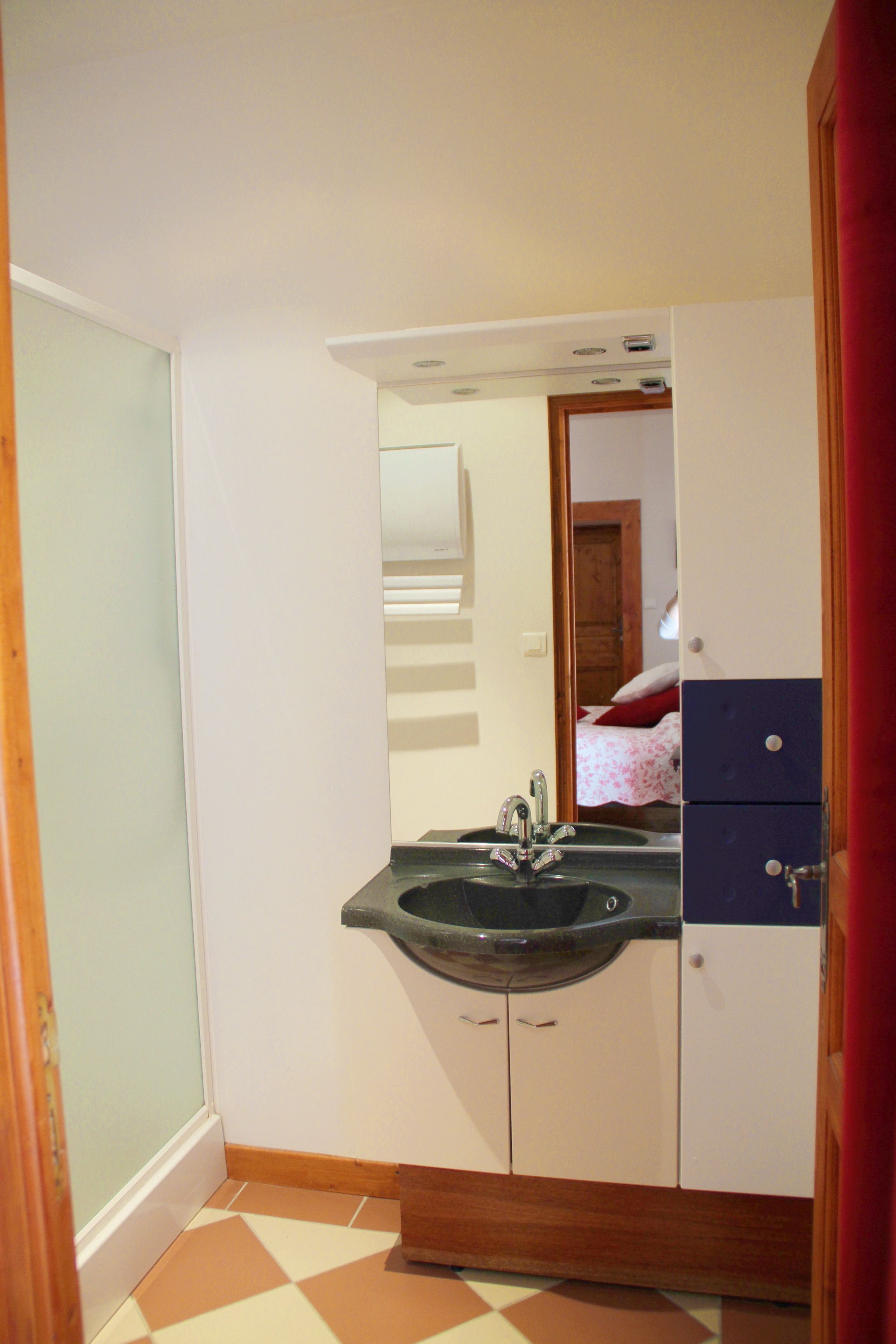 Une salle de bain avec un lavabo, un miroir et des placards.