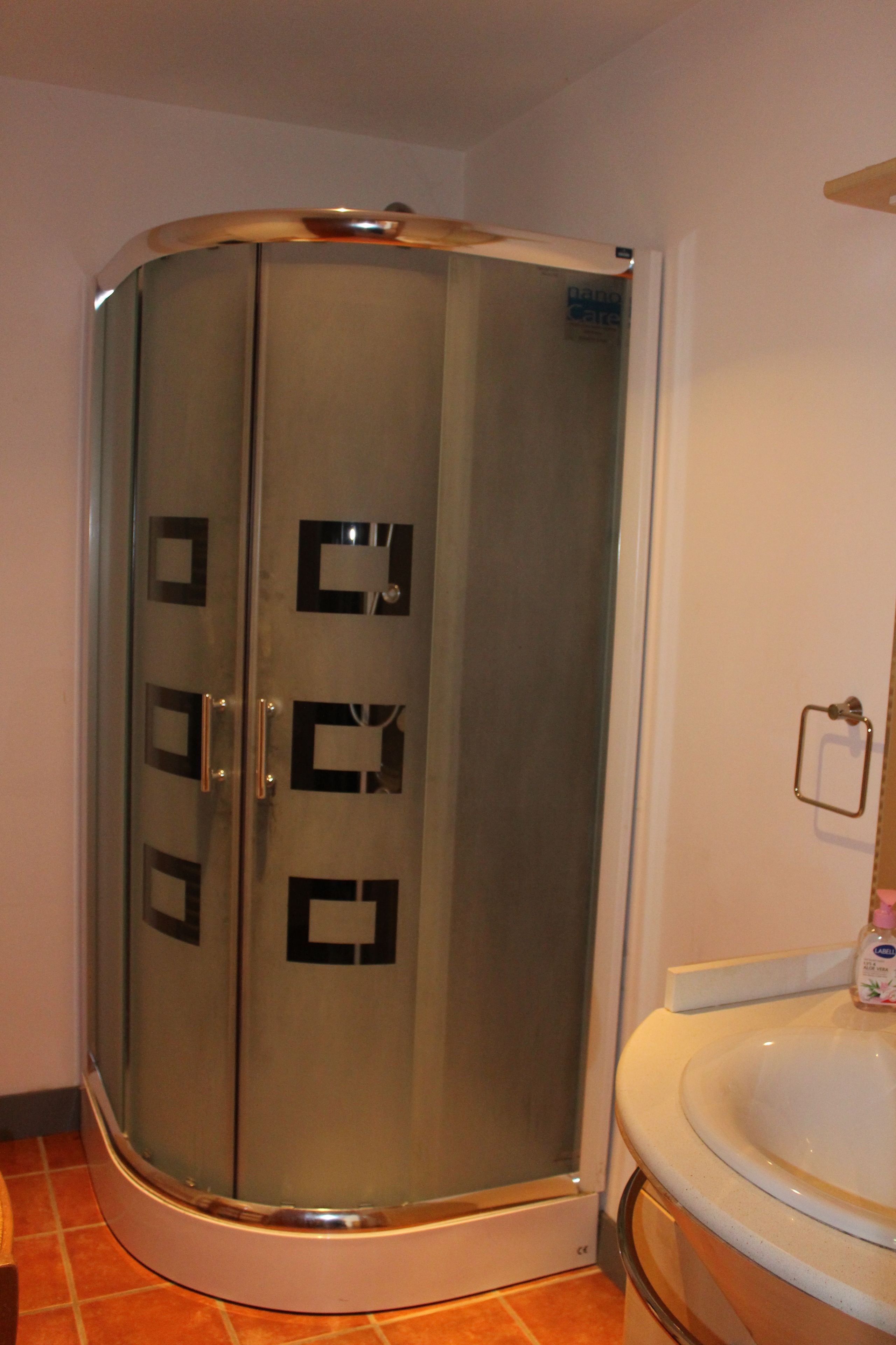 A bathroom with a glass-enclosed shower, a white sink, and a towel rack.