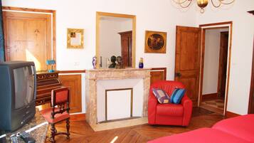 Ein Zimmer mit Kamin, einem roten Sofa, einem Fernseher und einer Holztür.
