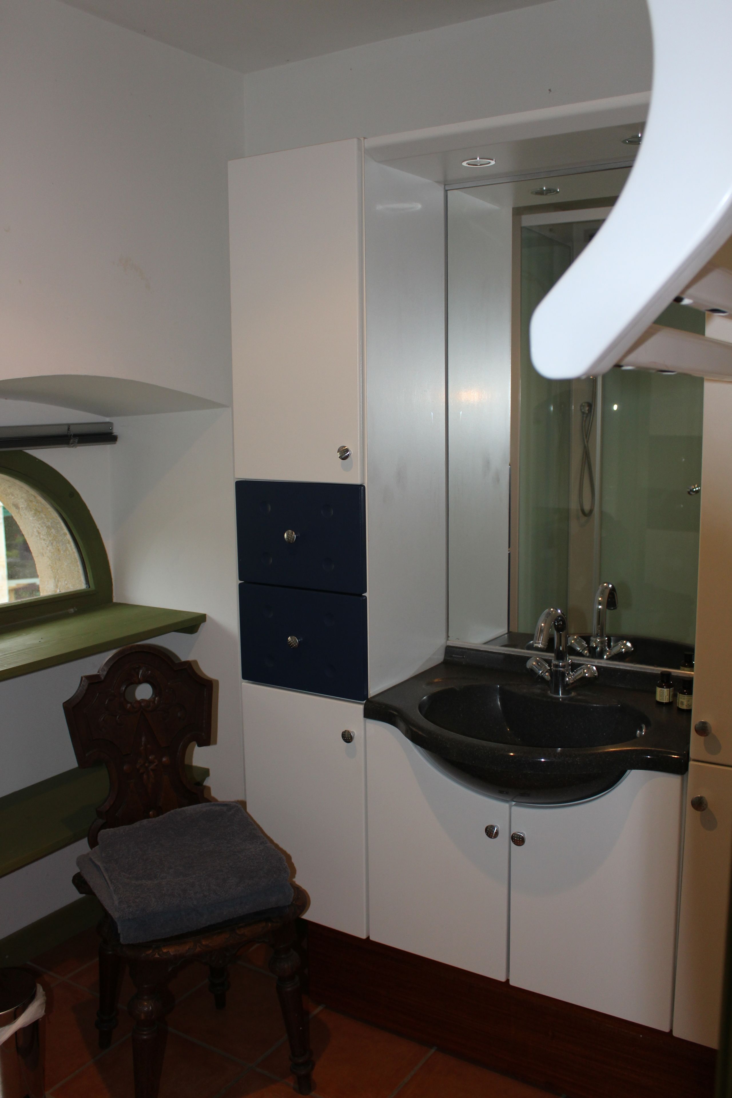 Un bagno con lavandino, specchio e mobiletto.