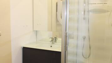 A bathroom with a glass-enclosed shower, a white sink, and a mirror above the sink.