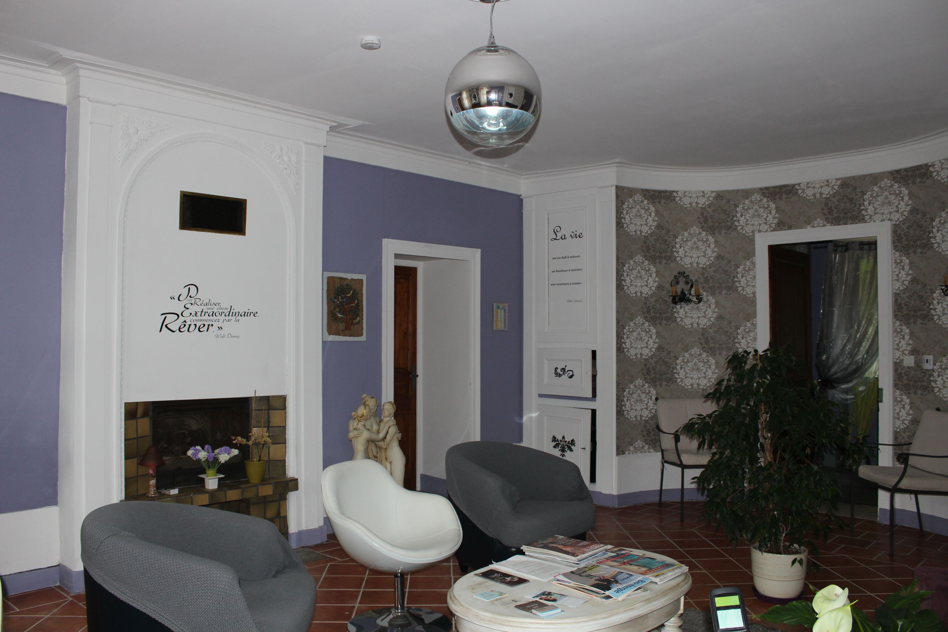 Una sala de estar con dos sillones, una chimenea, una planta grande en maceta y un candelabro.