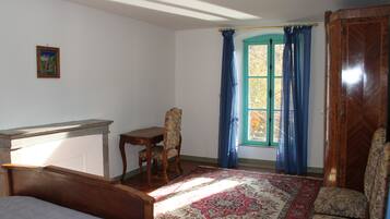 A room with a bed, a desk, a chair, and a window with curtains.