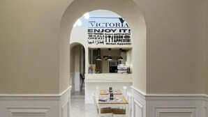 An interior hallway leading to a dining area with a sign reading "VICTORIA ENJOY IT!" and a doormat with "B&B VICTORIA" on it. - Victoria Hotel B&B (Naples)