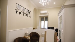 A modern living room with a sofa, a coffee table, and a fireplace. There is a kitchen area with a refrigerator and a sink. - Victoria Hotel B&B (Naples)