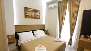 A hotel room with a bed, a painting, an air conditioning unit, and a desk with a mirror. - Victoria Hotel B&B (Naples)