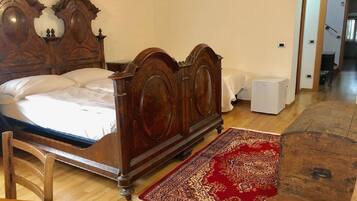 Une chambre à coucher avec un lit en bois, un tapis rouge à motifs, une chaise en bois et une table de chevet blanche.