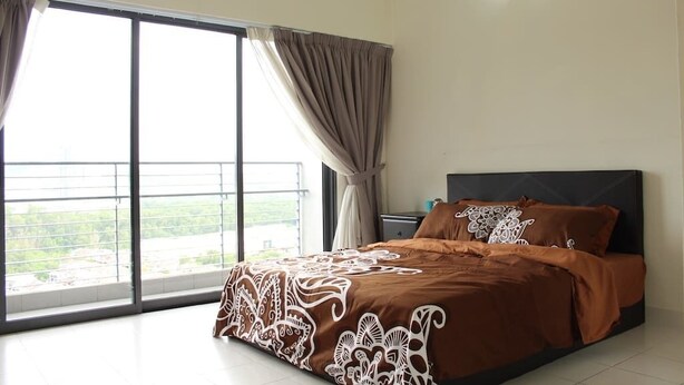 A bedroom with a large window, a bed with patterned bedding, a nightstand, and a wall-mounted light fixture. - Setia Walk by SYNC (Puchong)