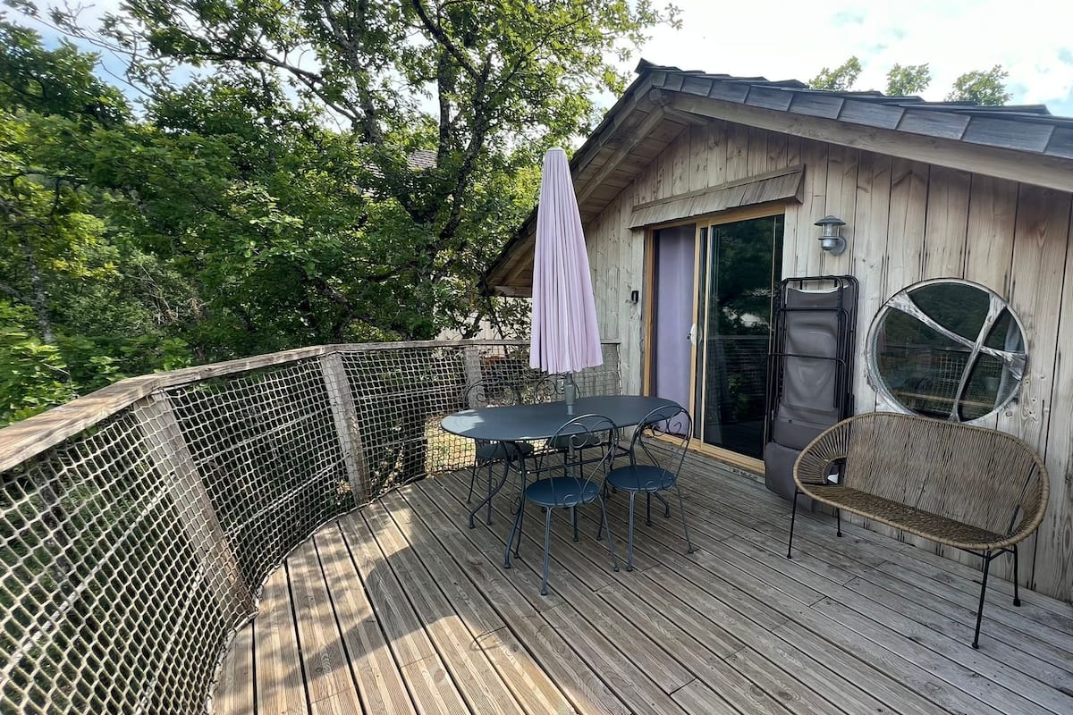 Une terrasse en bois avec une table et des chaises, un patio couvert et une grande fenêtre.