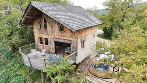 A wooden cabin with a balcony, surrounded by trees. - Cabanes et Lodges du Belvedere (Serrières-sur-Ain)