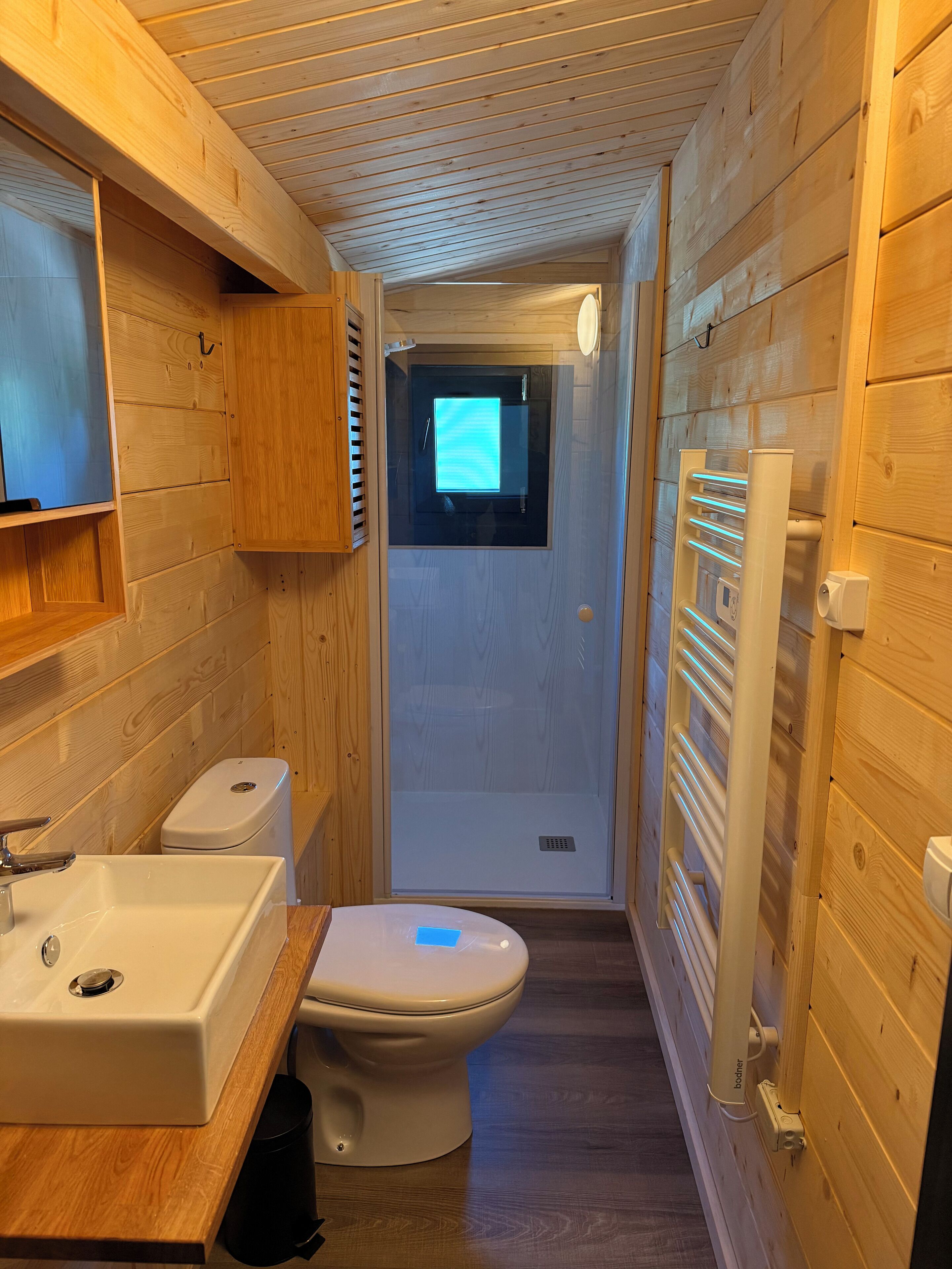 Une petite salle de bain en bois, équipée d’un lavabo, de toilettes et d’une petite fenêtre.