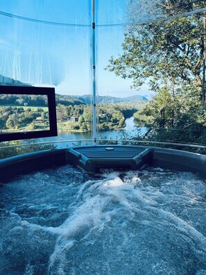 Un bain à remous avec vue sur une rivière et une forêt.