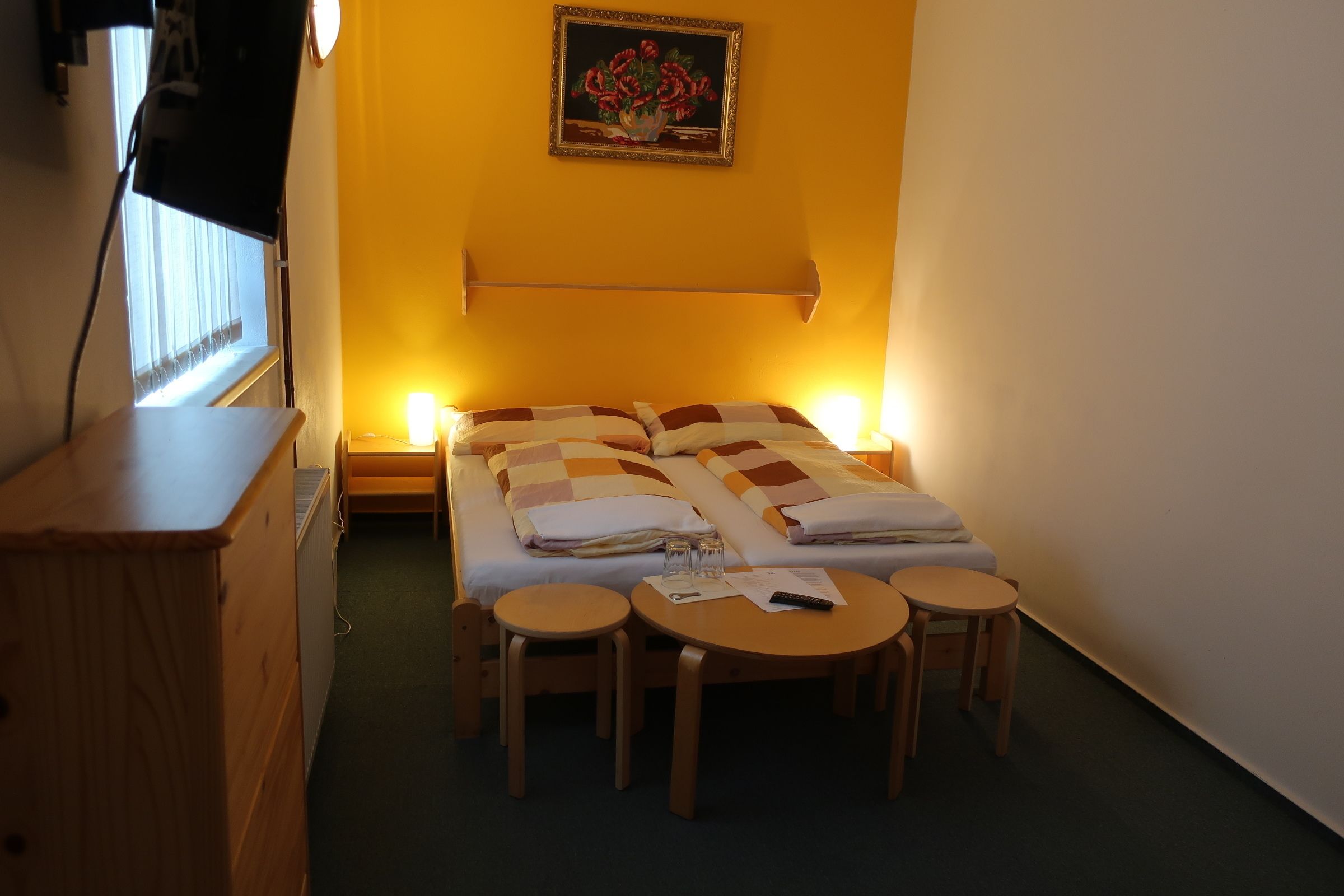 A room with a bed, two bedside tables, a desk, and a chair.