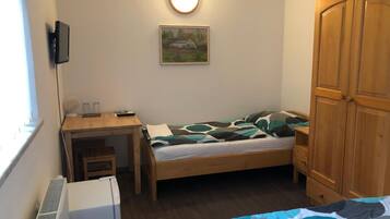 A small, tidy room with a bed, a desk, a chair, and a wardrobe.