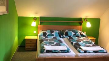 Une chambre avec un lit, deux tables de chevet et des murs verts.