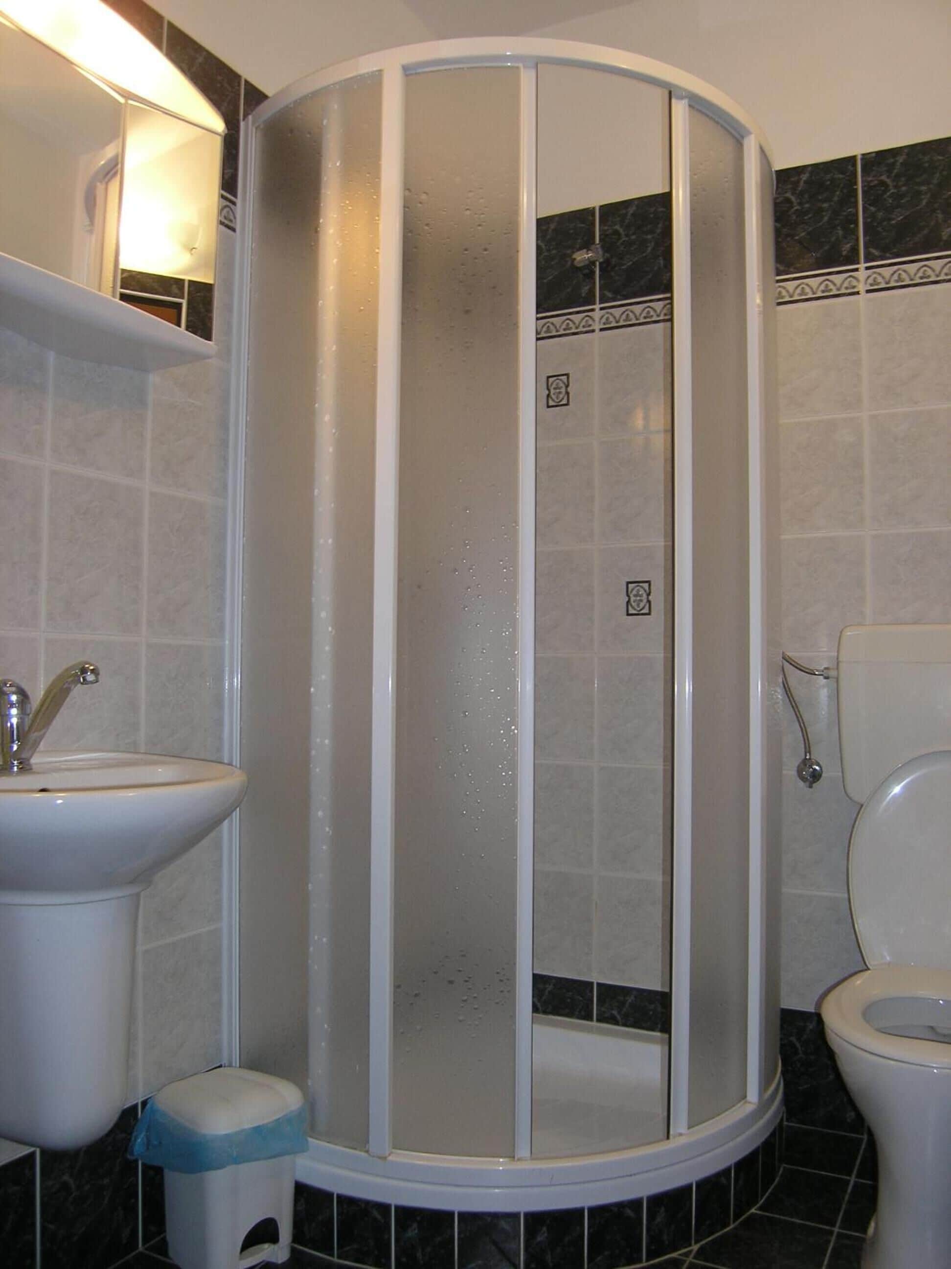 Un baño con cabina de ducha, lavabo e inodoro.