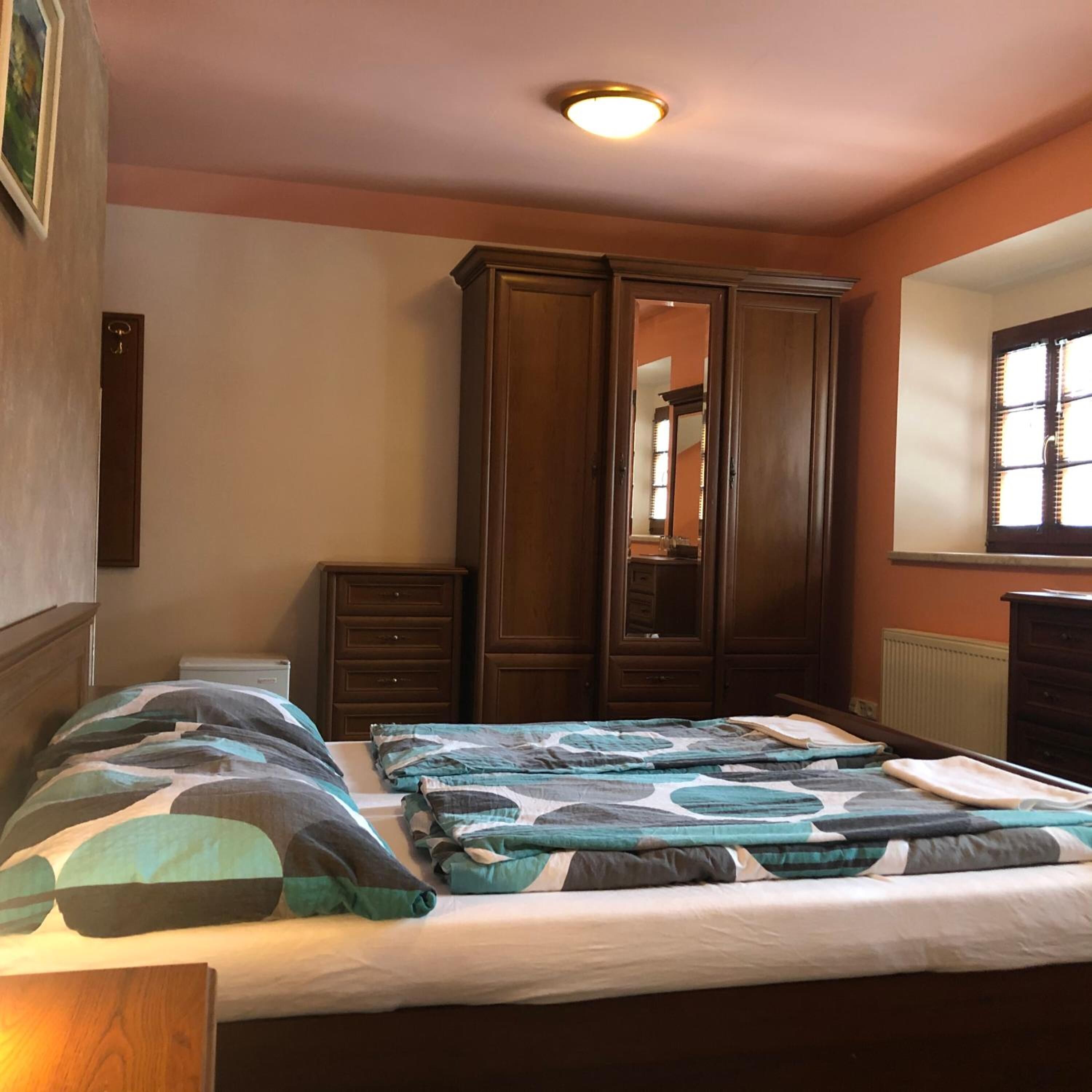 A bedroom with a bed, a dresser, a wardrobe, and a mirror.