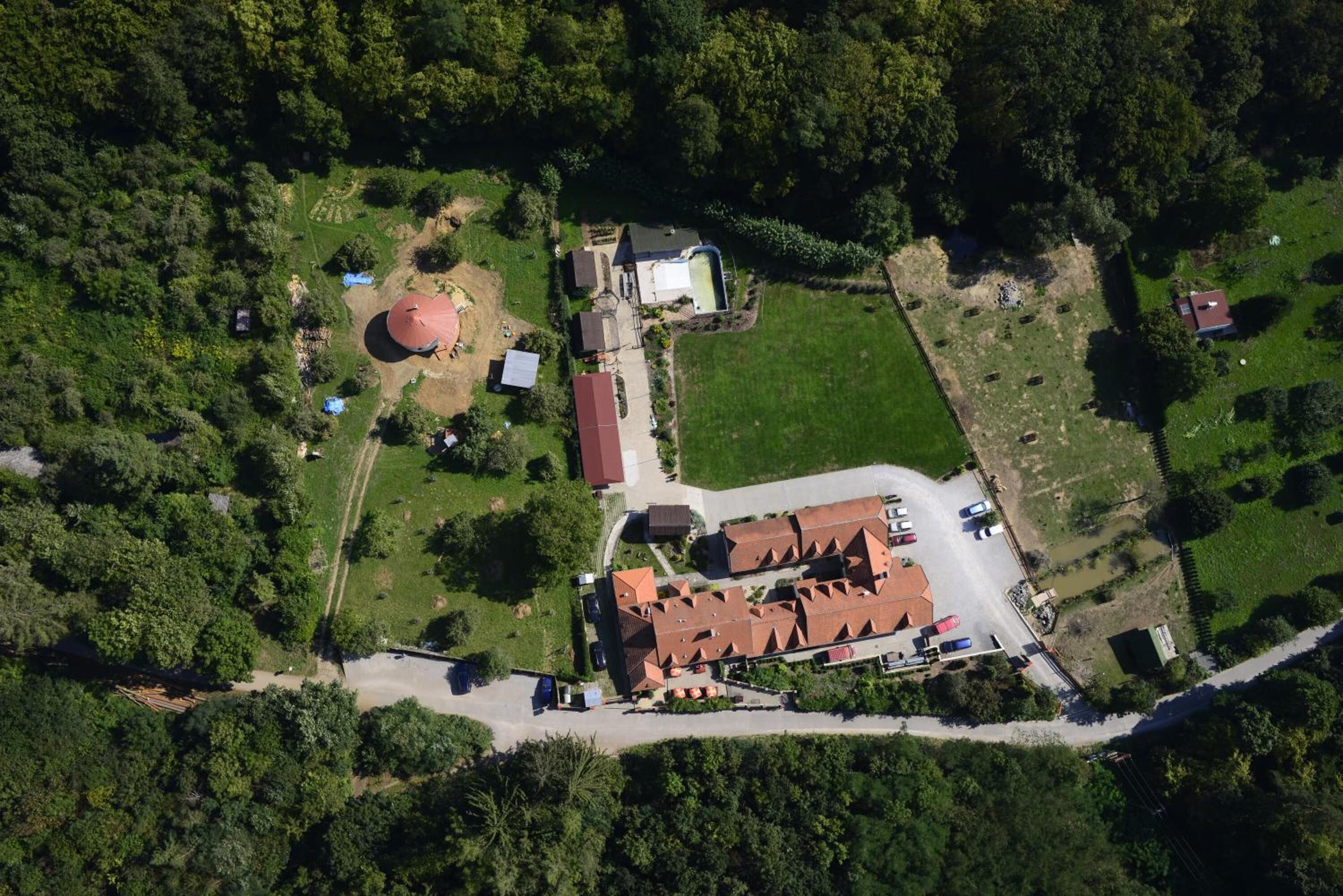 Vista aérea de una zona residencial con una casa grande, piscina y césped cuidado.