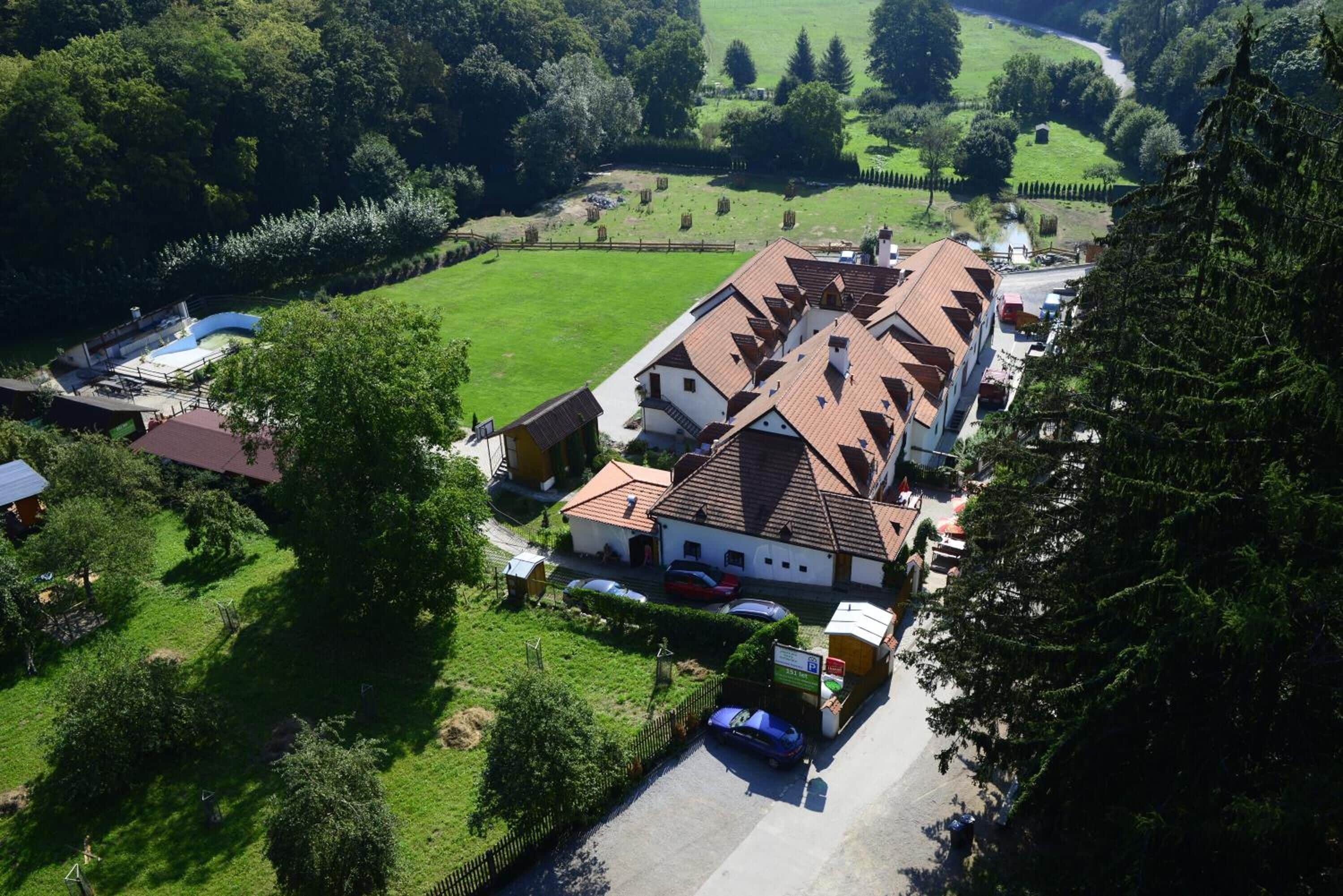 Een groot gebouw met meerdere daken, omringd door groene velden en bomen.