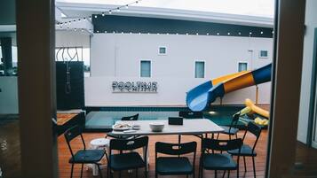 Relax and have fun in this outdoor dining area with a pool table, chairs, and a slide.