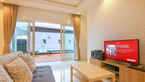 Uma sala de estar moderna com um sofá, uma mesa de centro e uma TV em uma parede de tijolos.