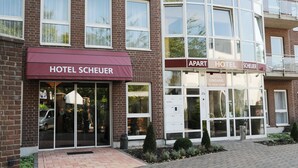 A hotel named 'Hotel Scheuer' with a red awning, a glass entrance, and a brick facade. - Apart Hotel Scheuer (Huerth)