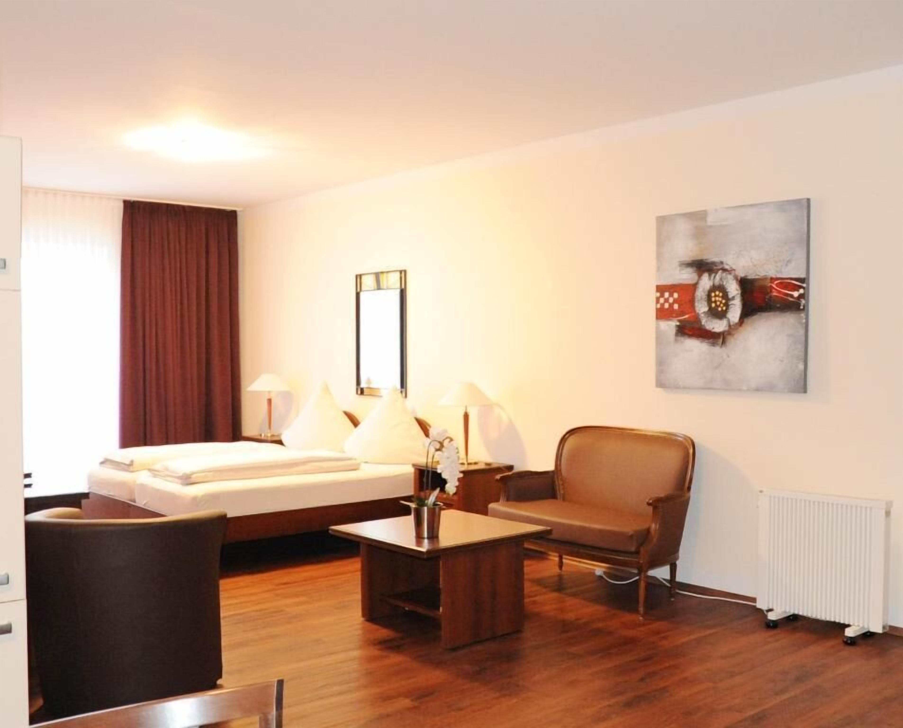 Een hotelkamer met een bed, een stoel, een tafel en een schilderij aan de muur.
