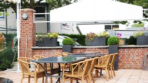An outdoor patio with a glass-top table and wicker chairs, surrounded by brick walls and potted plants. - Apart Hotel Scheuer (Huerth)
