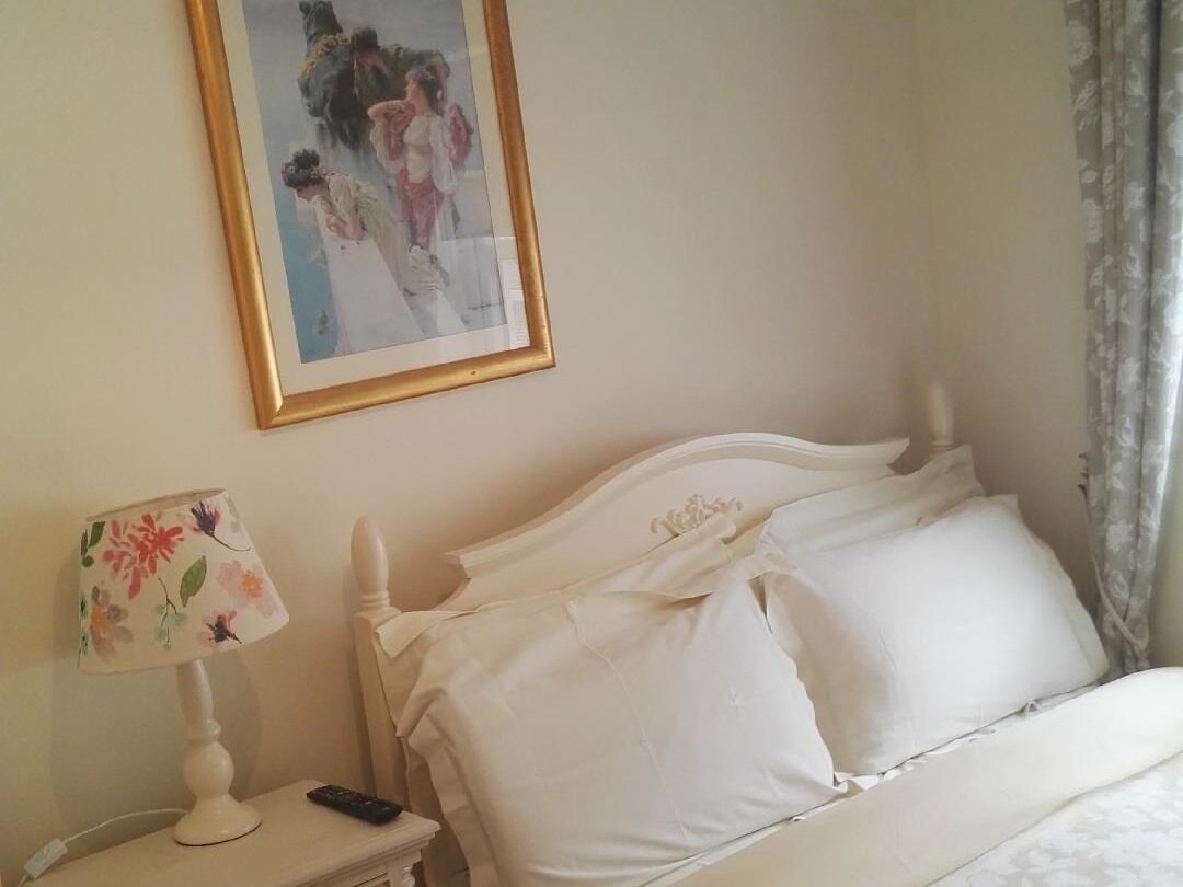 A hotel room with a bed, a nightstand with a lamp, and a framed picture on the wall.