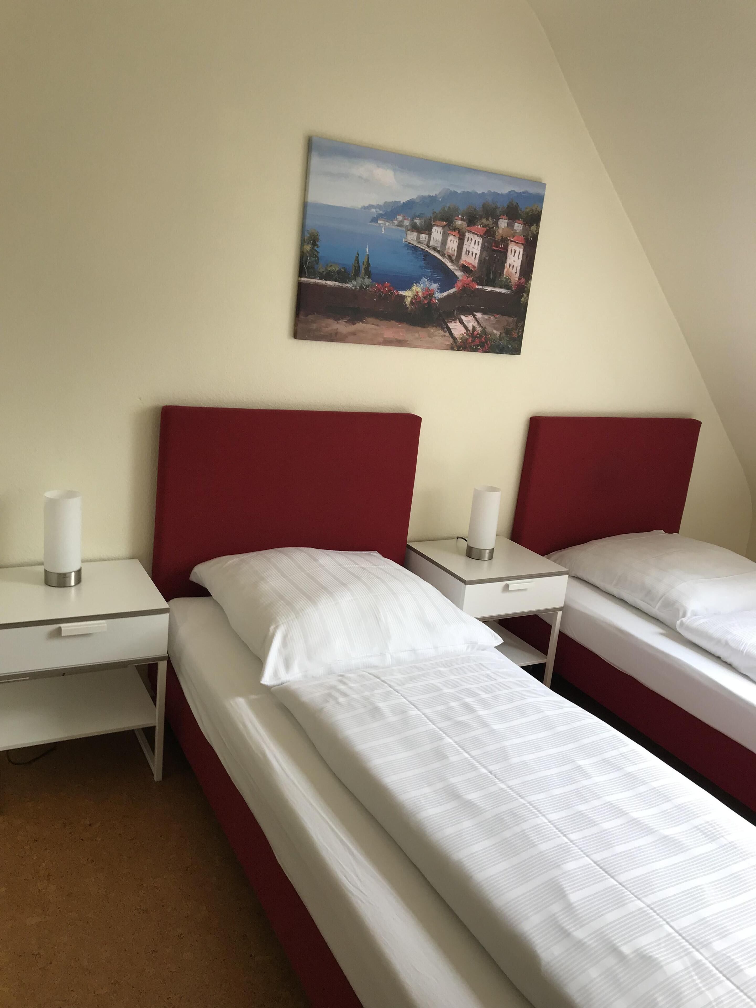 A hotel room with two beds, a desk, and a nightstand.
