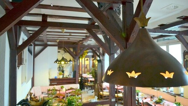 A restaurant with wooden beams and hanging pendant lights. - Pension Dessauer Hof (Halle (Saale))